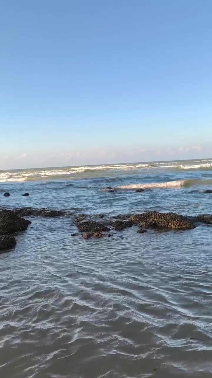 Onde delicate che si infrangono su litorale roccioso al tramonto