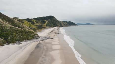 coastal view of a new zealand beach with hills and clouds
