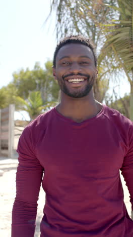 vertical video of portrait of happy african american man at beach house