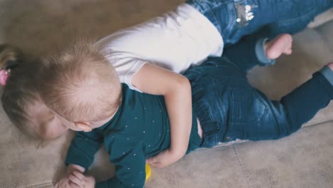 playful-girl-hugs-little-brother-spending-time-on-large-bed