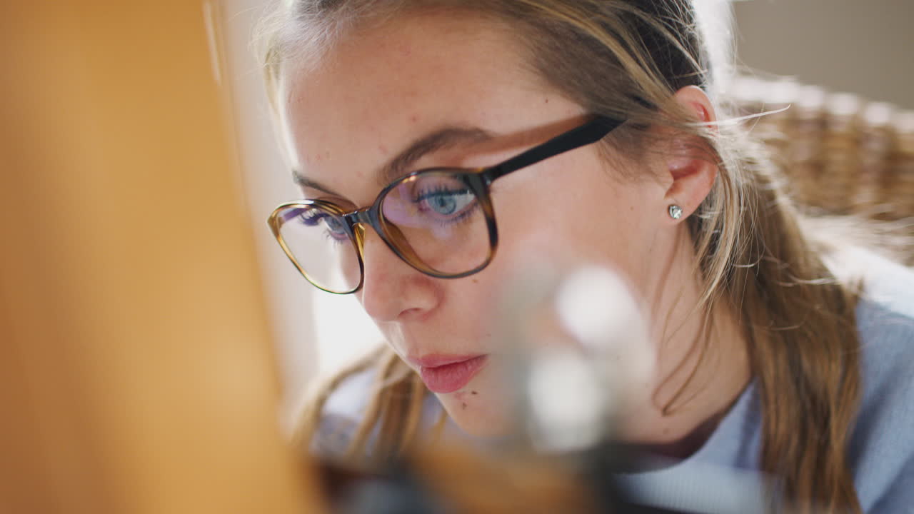 cerca en la cara de una artista adolescente que trabaja detrás de un caballete