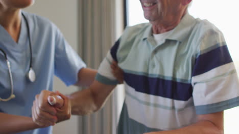 young biracial woman assists a senior caucasian man in a medical office