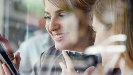 Dos-Mujeres-Usando-Una-Tableta-Digital-Bebiendo-Café-En-La-Cafetería