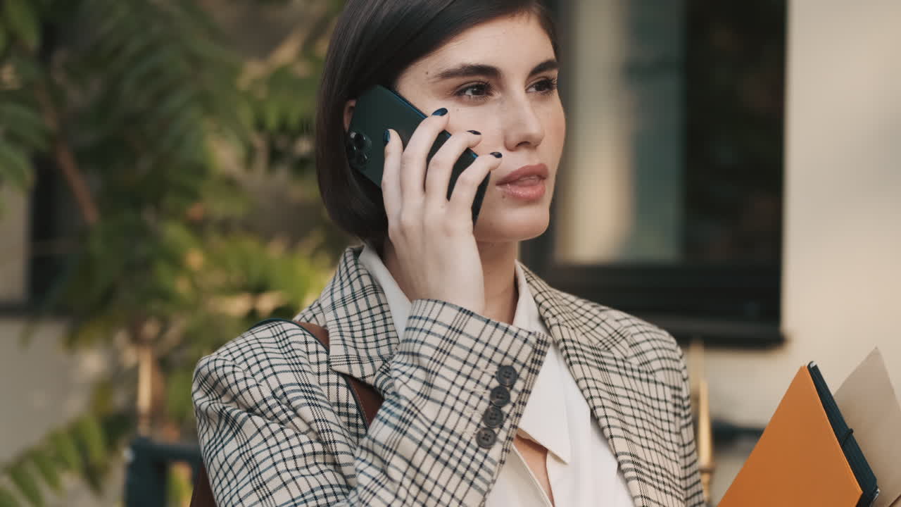 una mujer elegante haciendo una llamada de negocios al aire libre.
