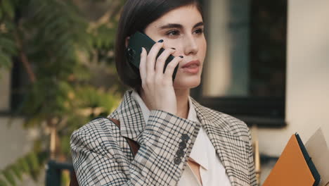 una mujer elegante haciendo una llamada de negocios al aire libre.