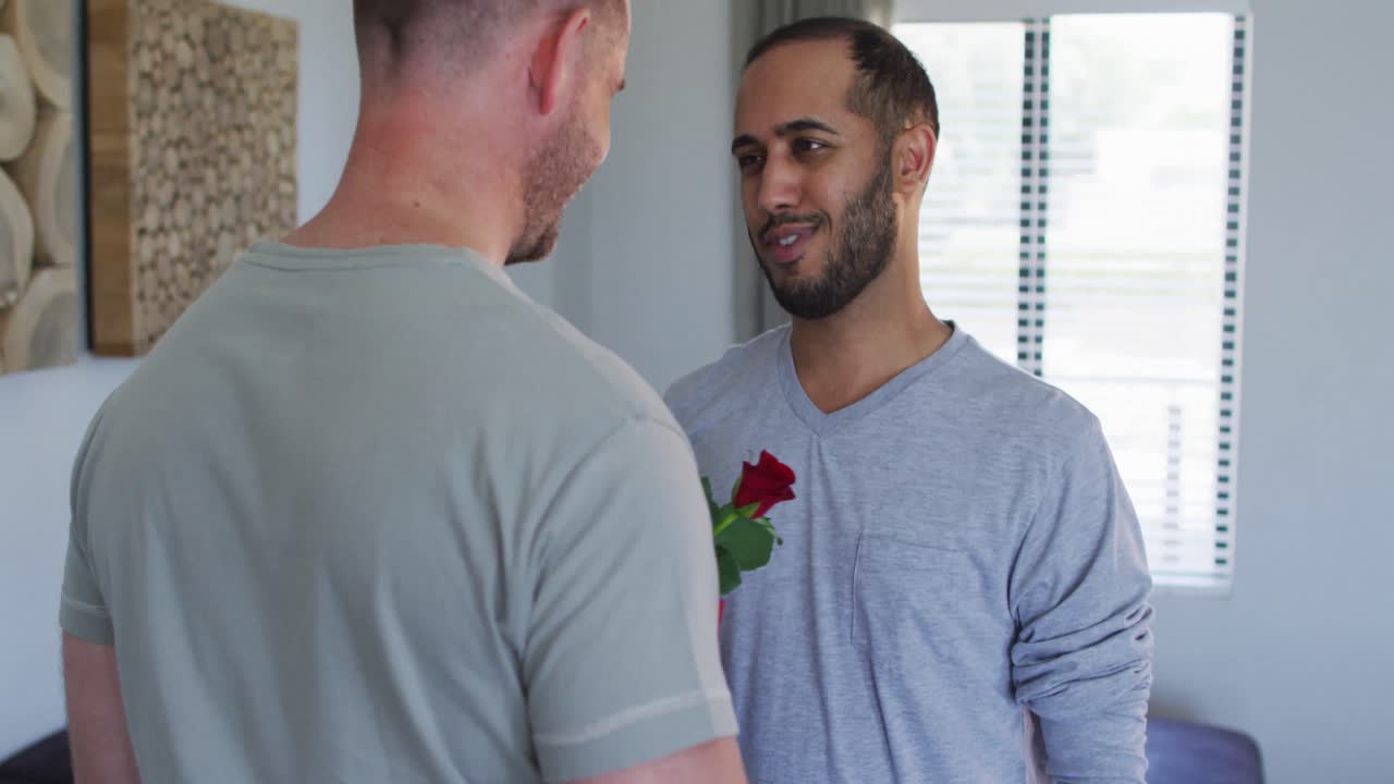 pareja de hombres homosexuales multiétnicos abrazando a uno sosteniendo un regalo