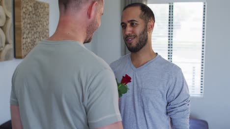 multi ethnic gay male couple embracing one holding a gift