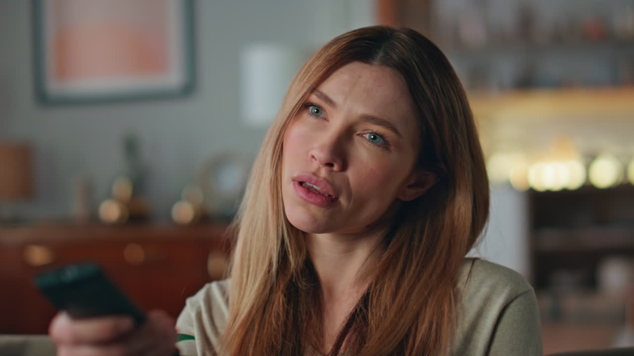 Bored woman switching tv channels at home closeup. Girl choosing movies on couch