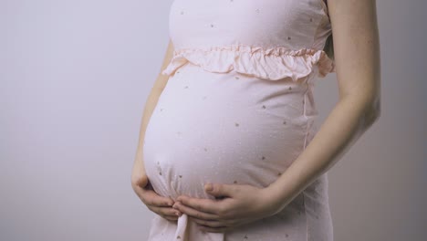 mujer embarazada en vestido toca la protuberancia del bebé en un primer plano de la pared