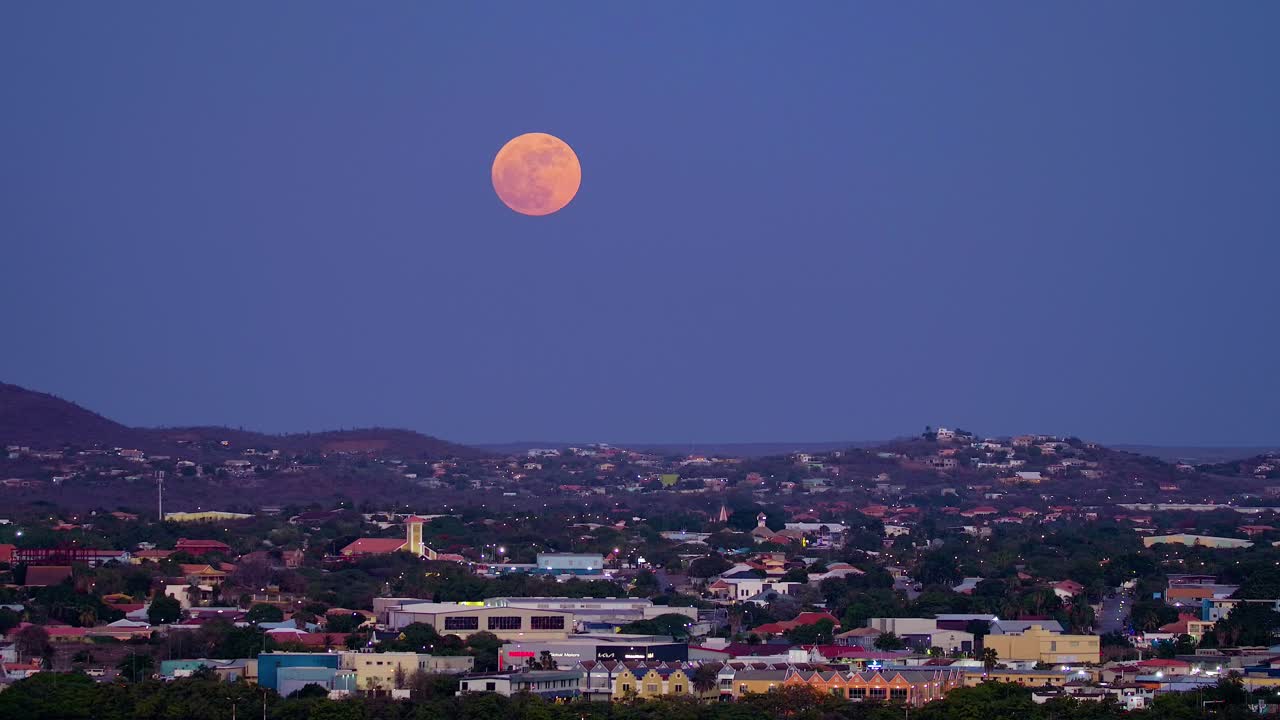 큰 파란색 슈퍼문이 빨간색으로 빛나고, 윌렘스타드 쿠라소 위에서 오른쪽에서 왼쪽으로 판