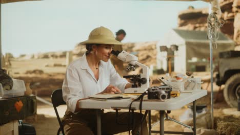 archeological digging site: great female archaeologist doing cultural research, discovers ancient civilization historical artifacts, fossil remains at excavation site, study it under microscope