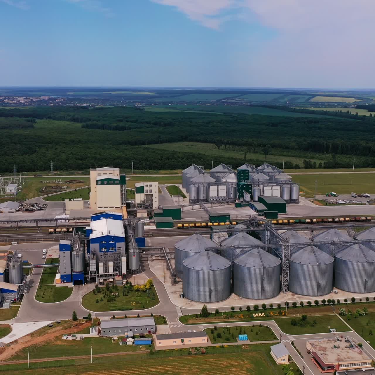 Industriestandort für die Getreidelagerung. Silberne Tanks und andere Werksgebäude von außen aus der Vogelperspektive. Naturlandschaft im Hintergrund