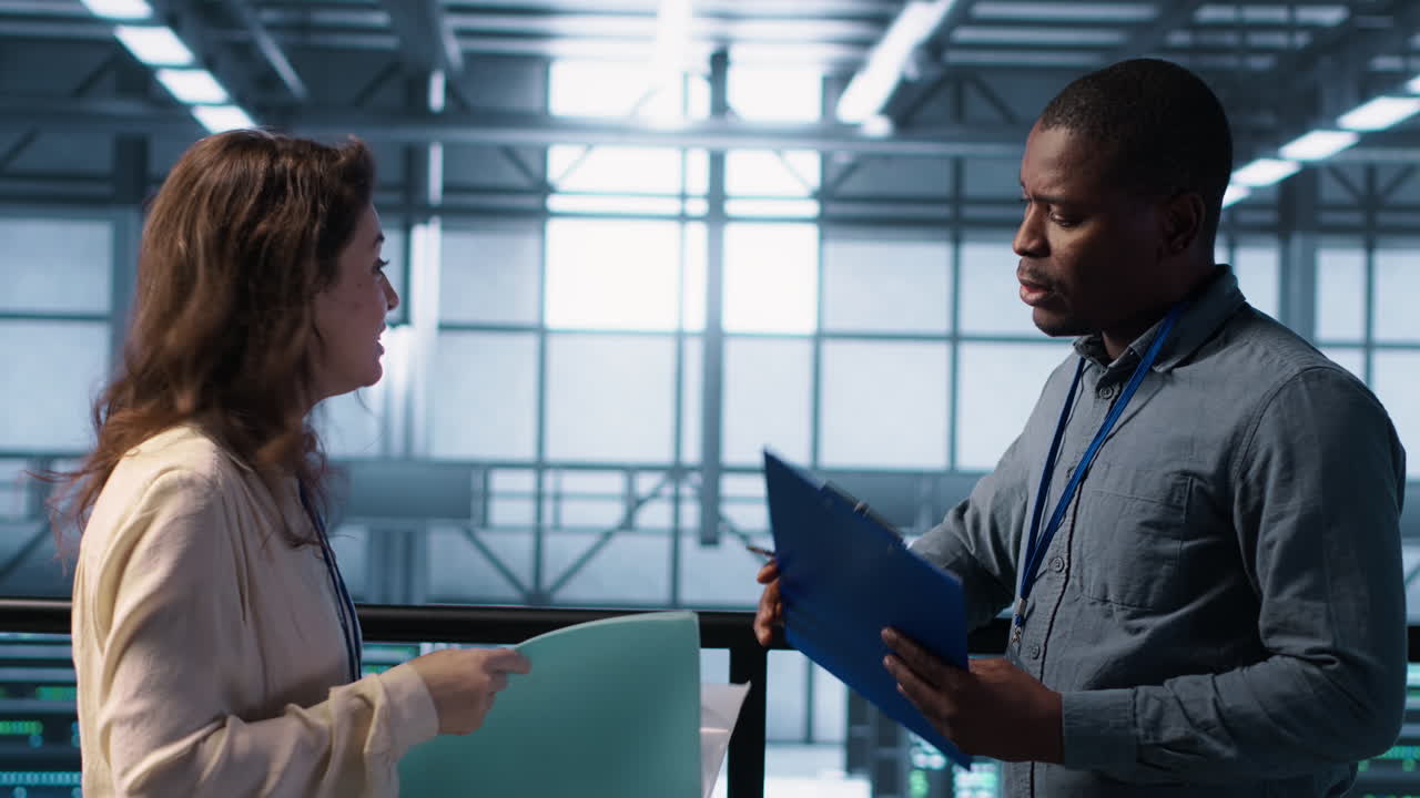 ingeniero de centro de datos saludando a un colega, examinando el papeleo de diagnóstico del sistema