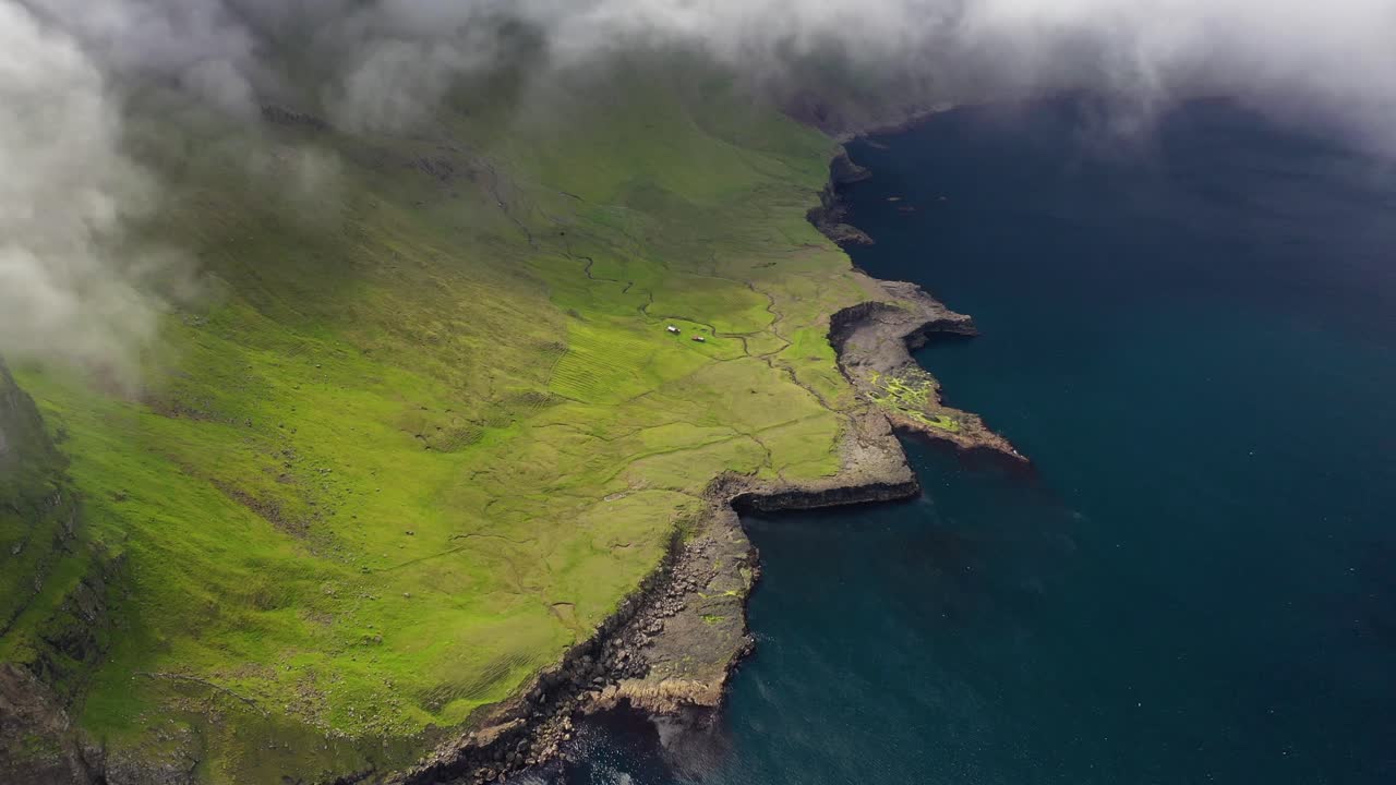 Vista aérea costeira acima dos penhascos acidentados das Ilhas Faroé, através das nuvens.