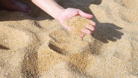 manos interactuando con la arena en una playa soleada