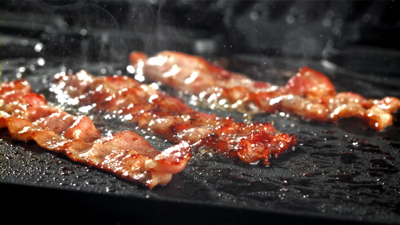 Deliziose strisce di pancetta che sfrigolano su una piastra calda