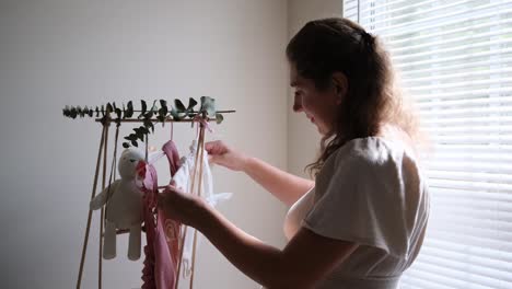 a loving mom is organizing her babys clothes beautifully in the warm and natural light a serene and blissful moment where a mom happily hangs baby clothes with joy in soft beautiful natural light