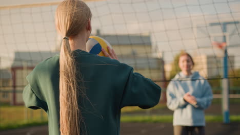 volleyball players practicing in open field with blurry view of someone pushing bicycle and other people walking, sunlight creating warm glow around them
