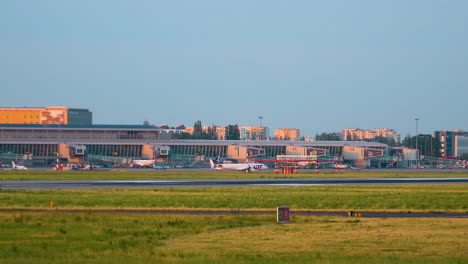 warsaw chopin airport airfield at sunset - passenger airplane moving along the aerodrome towards runway - wide low angle static