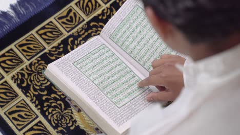 over the shoulder shot of indian man reading quran holy book