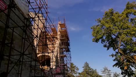metallic scaffolding against an old ruins wall in the forest