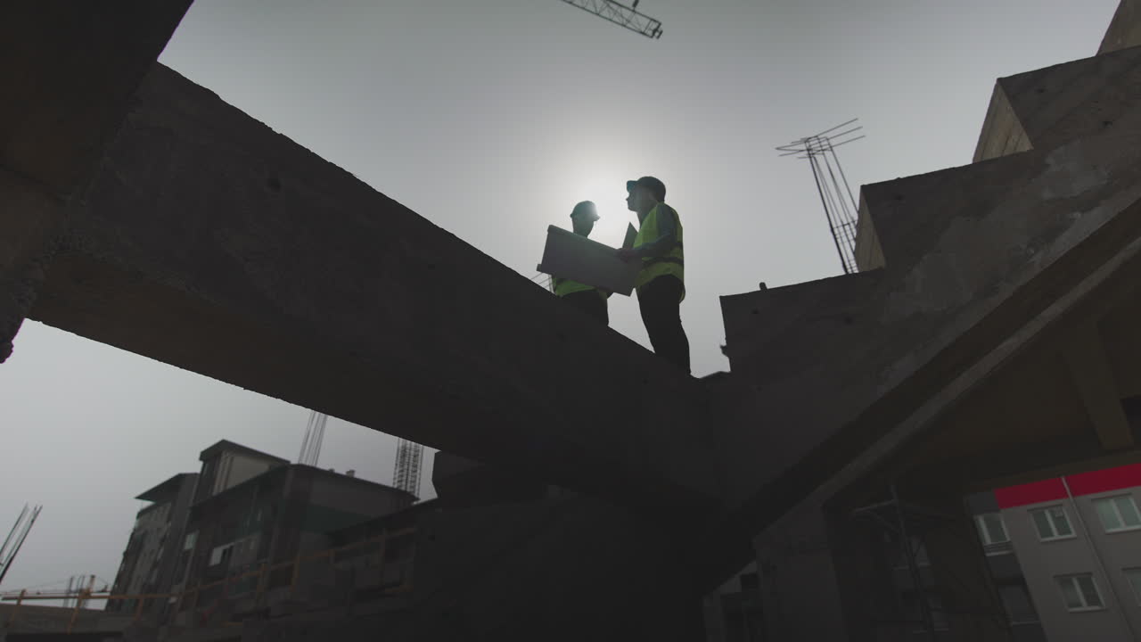Construction Workers Examining Blueprint on a Building Site