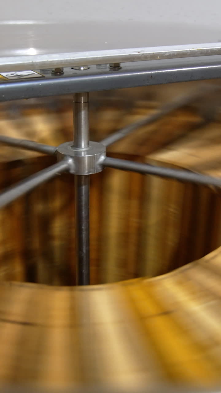 Organic honey frames spinning in the centrifuge apparatus. Special device for extracting honey at bee farms at work. Vertical video