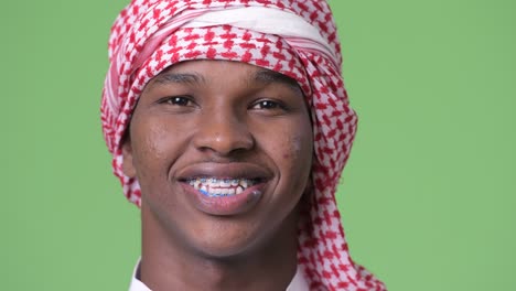 young african man wearing traditional muslim clothes against green background