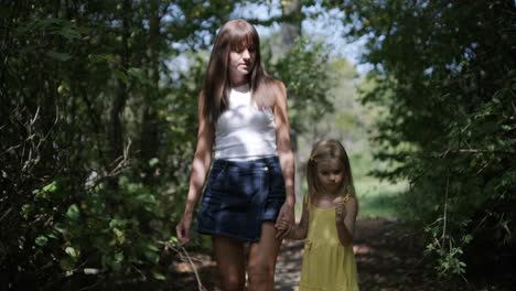 mother and daughter walking on a path in the forest