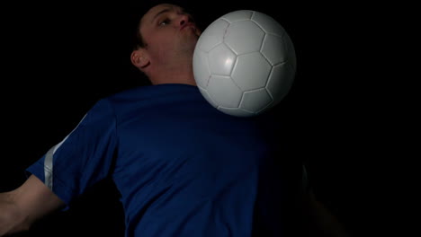 footballer controlling the ball with his chest on black background