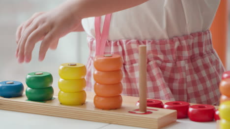 little toddler girl's hand stacking wooden colorful rings in slow motion