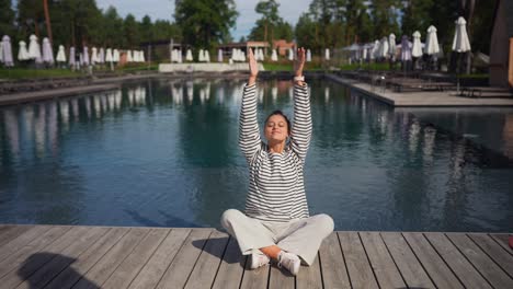 woman meditating by the pool