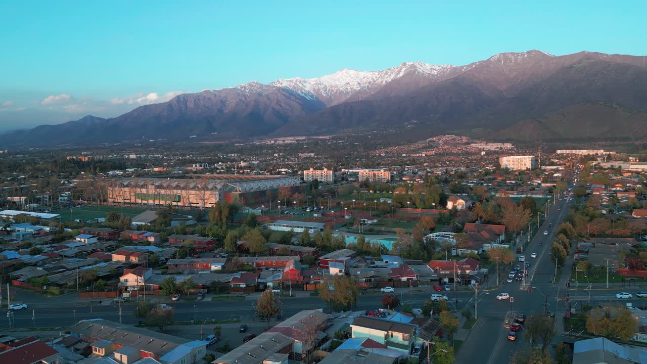 Ripresa ascendente sopra le strade residenziali di Santiago con le Ande innevate all'ora d'oro. Santiago, Cile.