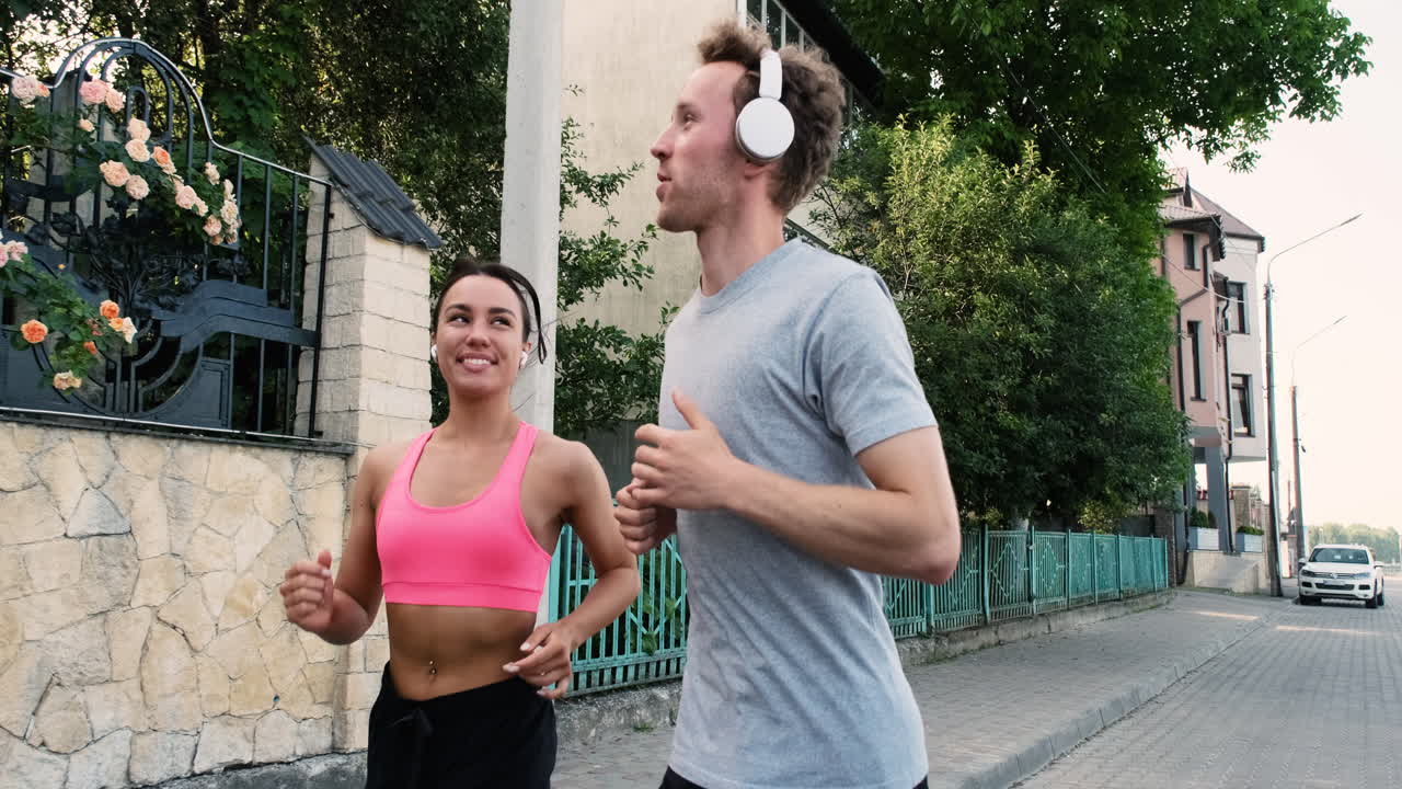 bella corredora con airpods y joven deportista con auriculares corriendo juntos en la ciudad 1
