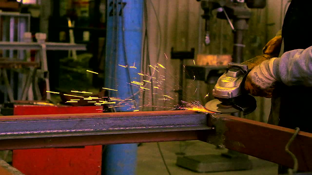 slow motione for a worker using the grander in a  metale workshop.