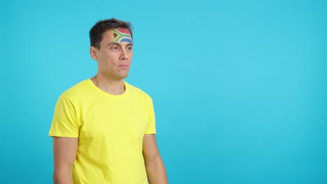 happy man with south african flag painted on face looking away
