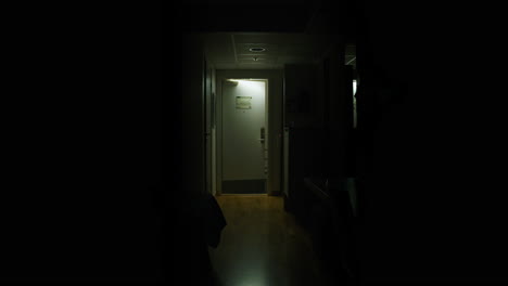 young man leaving dark hotel room, not looking back while door shuts, slow motion