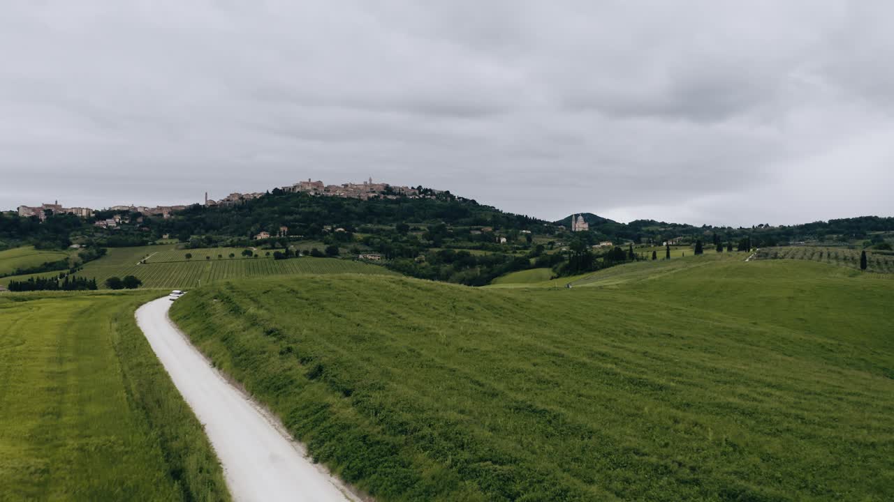 Drone shot of a lone winding road cutting through Italy's lush farmland