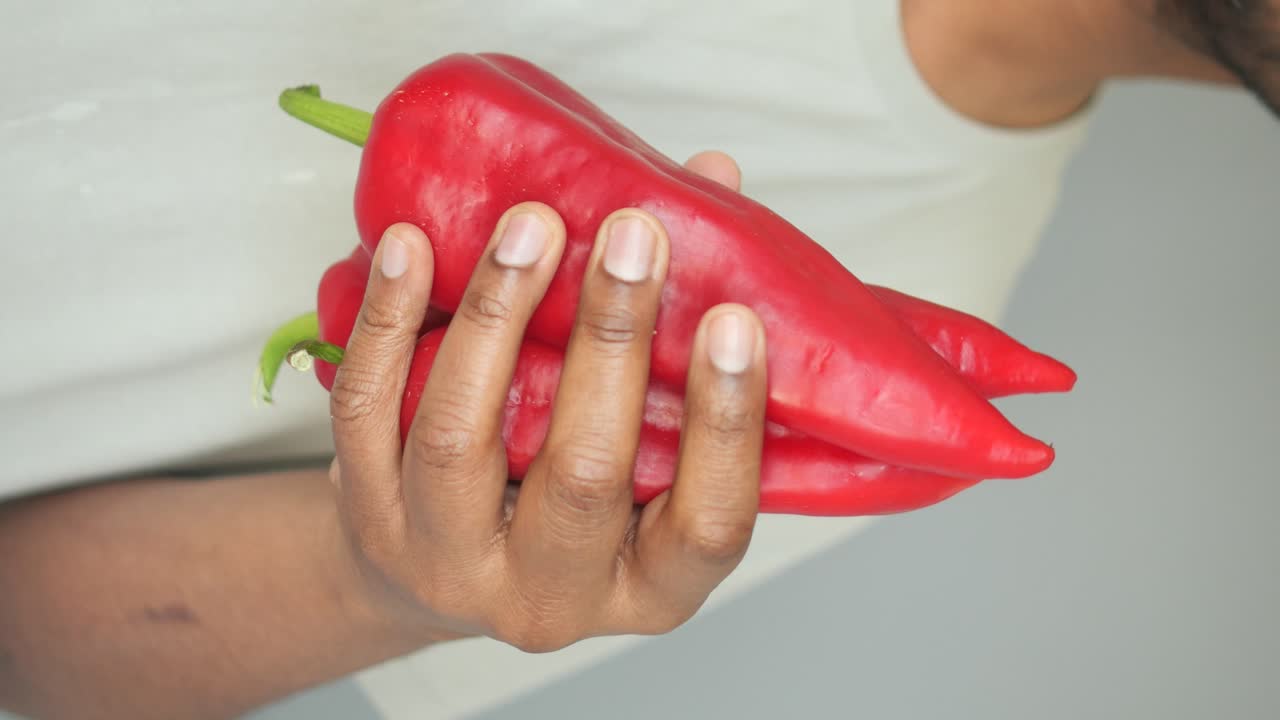 Person holding red bell peppers