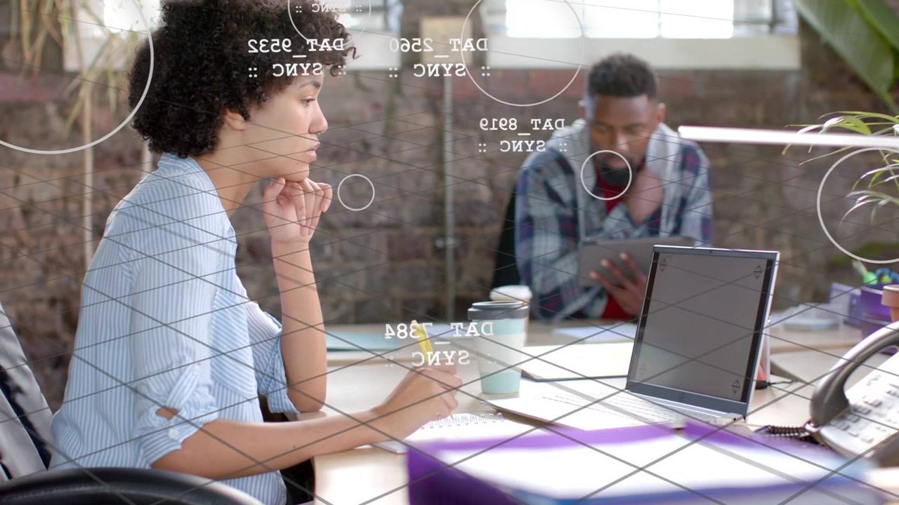 Woman writing, pen touching notes causing grid overlays marking laptop and tablet, aiding design