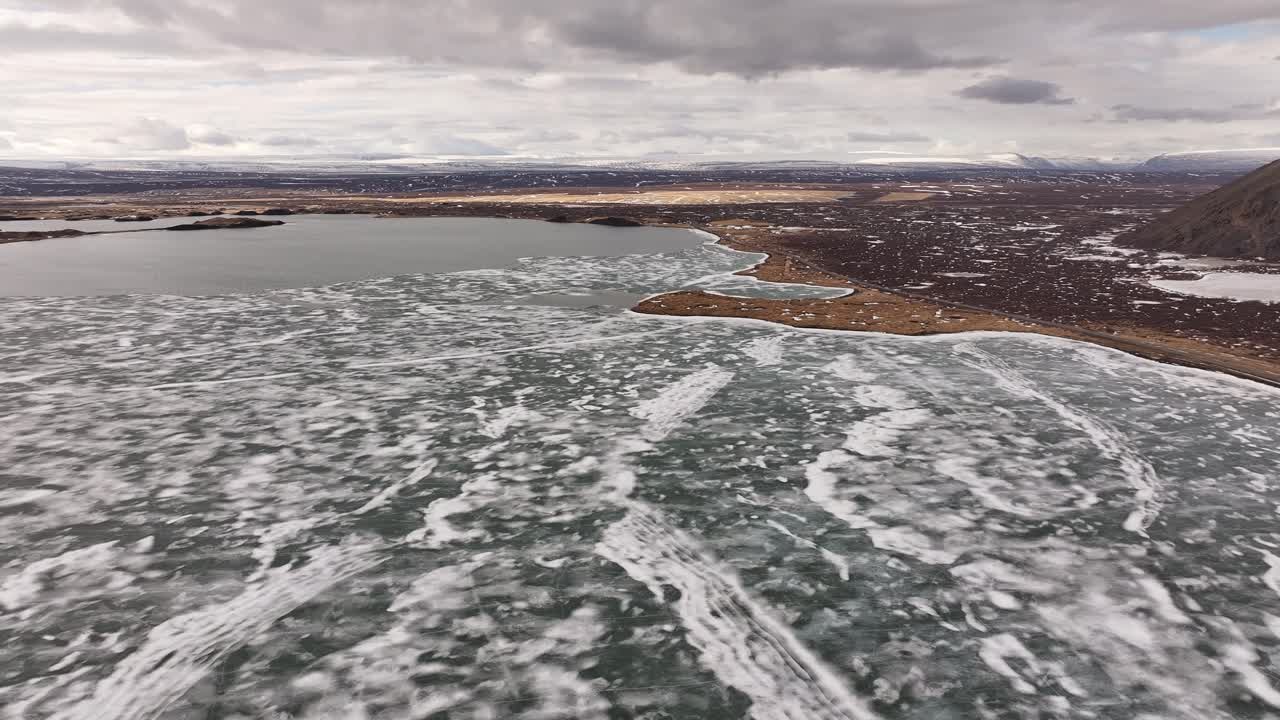 Ice-covered Lake Mývatn near Skútustaðir with dramatic shoreline and distant lava fields. Reykjahlíð, Iceland