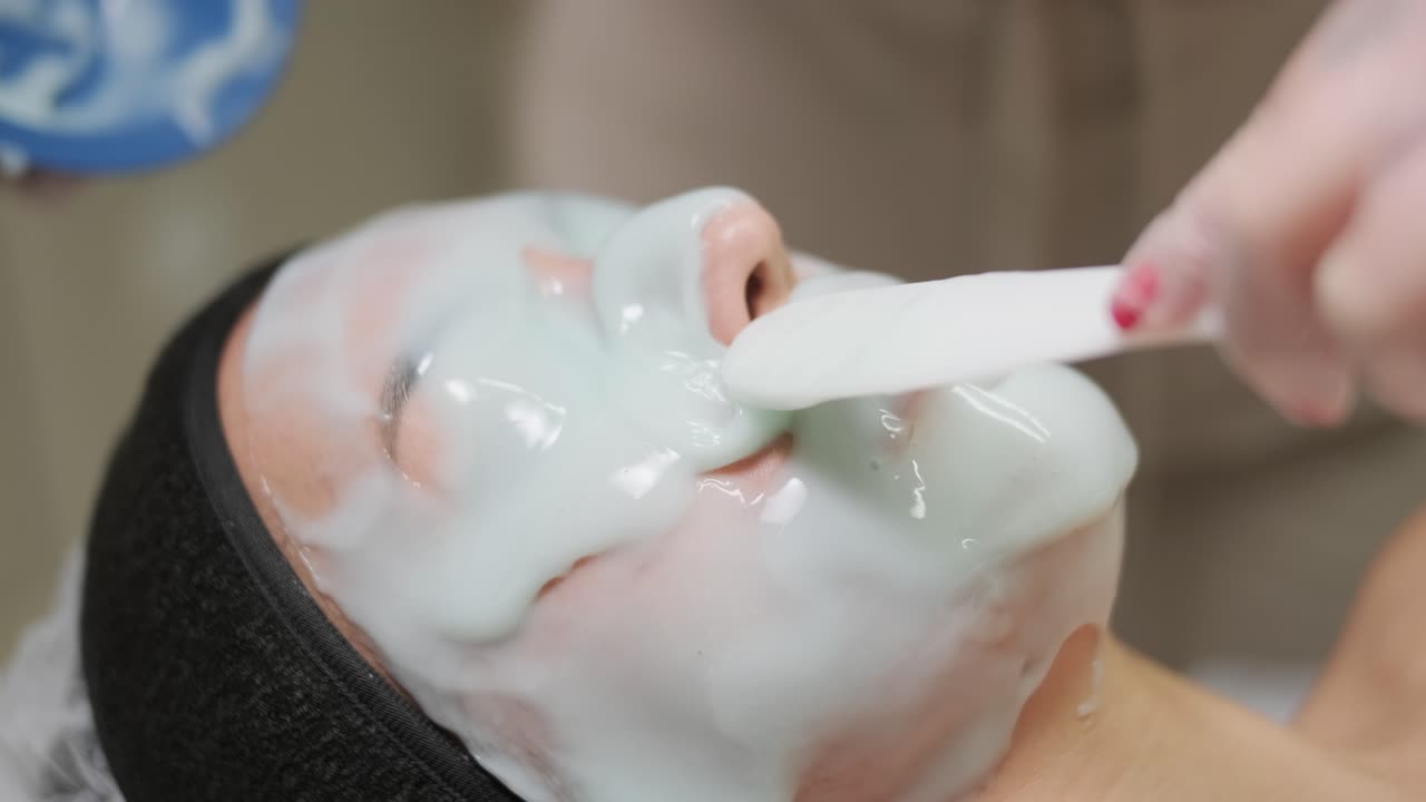 mujer hermosa con máscara facial en un salón de belleza