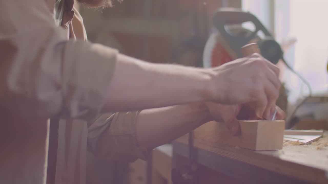Woodworker Cutting Plank with Hand Saw