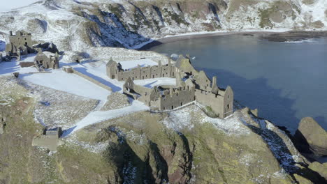 vista aérea de las ruinas del castillo de dunnottar rodeadas de nieve en un soleado día de invierno, nr stonehaven, aberdeenshire, escocia