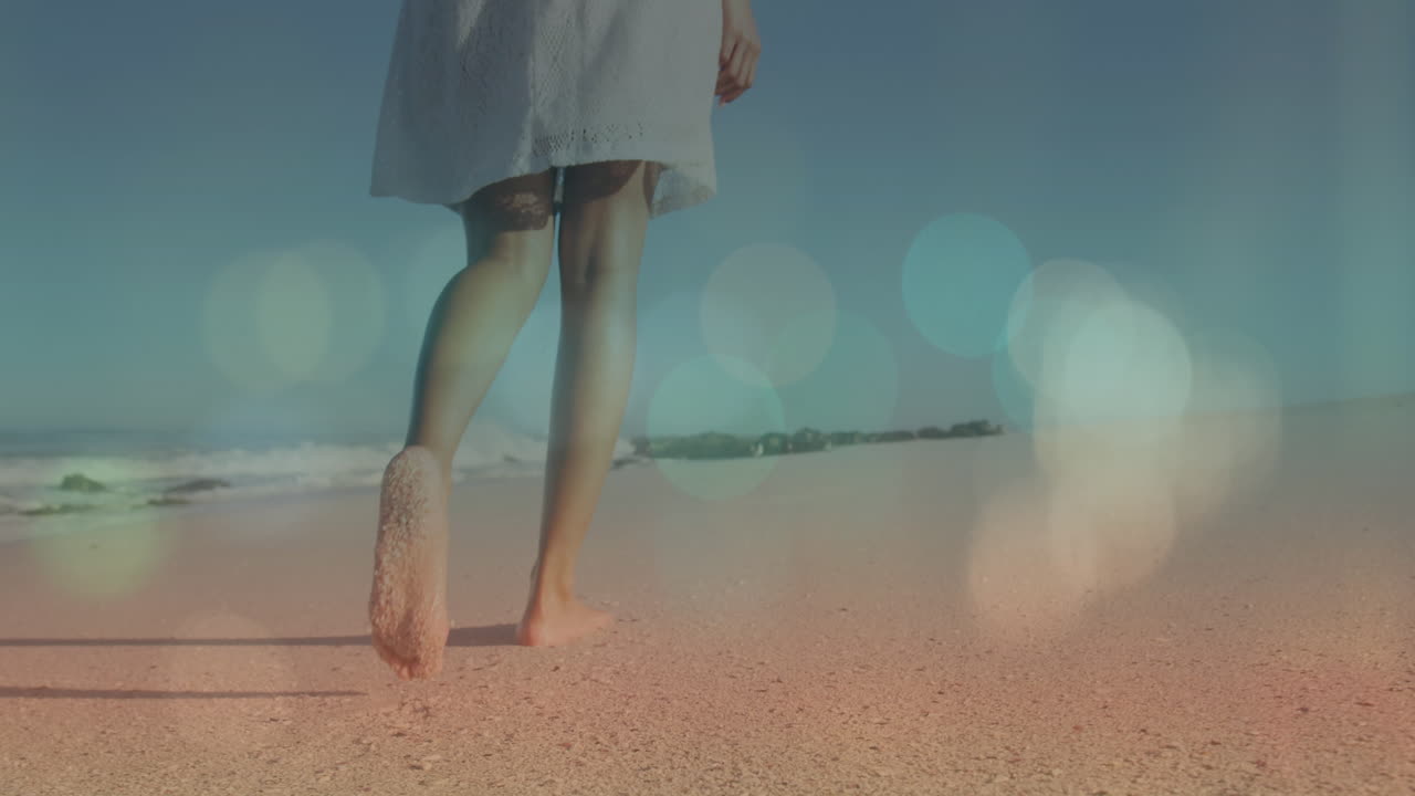 모래 해변에서 맨발로 고 있는 두 인종의 젊은 여성의 낮은 부분에 대한 렌즈 플레어의 애니메이션