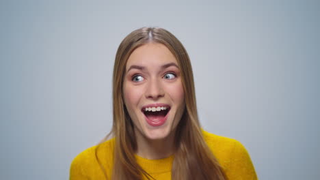 portrait of positive woman showing thumbs up at camera on grey background.