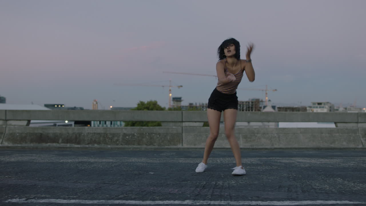 mujer bailarina atractiva bailarina callejera hispana en la ciudad realizando movimientos contemporáneos de hip hop disfrutando de la expresión de la danza moderna al atardecer