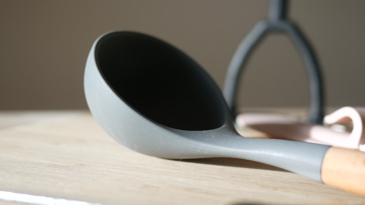 cuchara de silicona gris en tabla de corte de madera