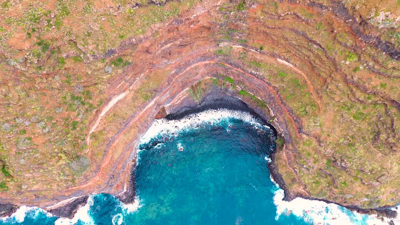 Hidden cove on Tenerife with waves crashing against rugged cliffs from above