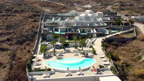 orbit view of a luxurious traditional hotel resort with a woman swimming in santorini, greece